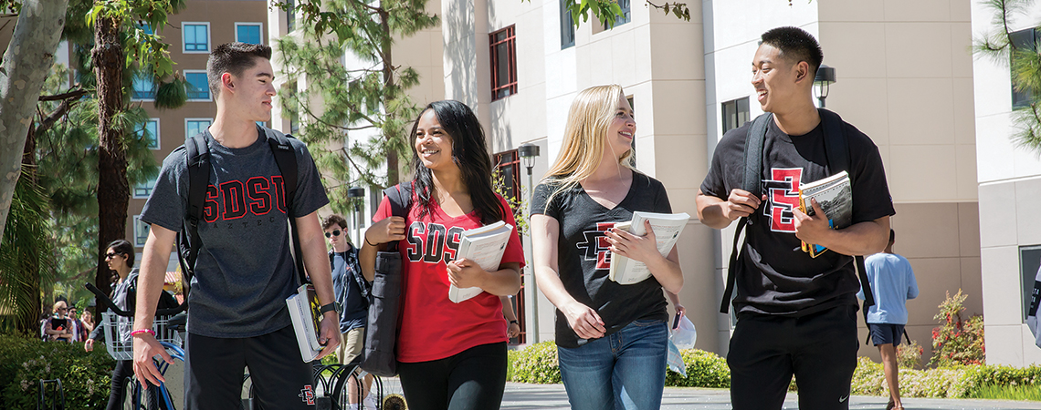Photo of students walking with their textbooks. Photo of students walking with their textbooks.